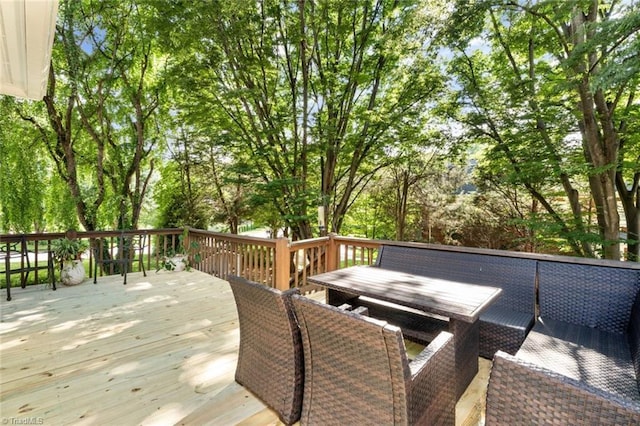wooden terrace with outdoor dining area and view of wooded area