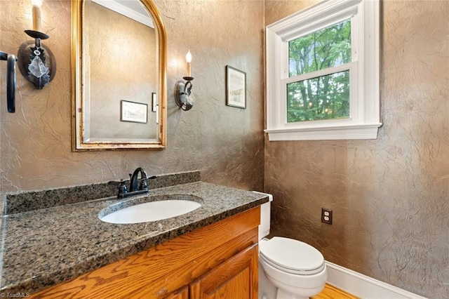 bathroom featuring vanity, toilet, and a textured wall