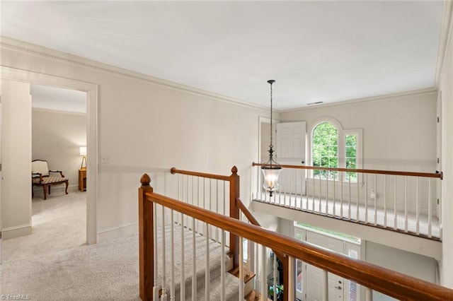 corridor featuring carpet floors, ornamental molding, an upstairs landing, and baseboards