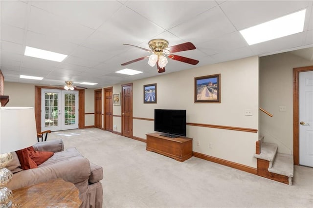 living room with french doors, ceiling fan, carpet floors, a drop ceiling, and stairs