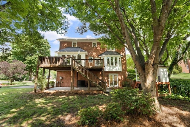rear view of property featuring french doors, a deck, brick siding, and a patio