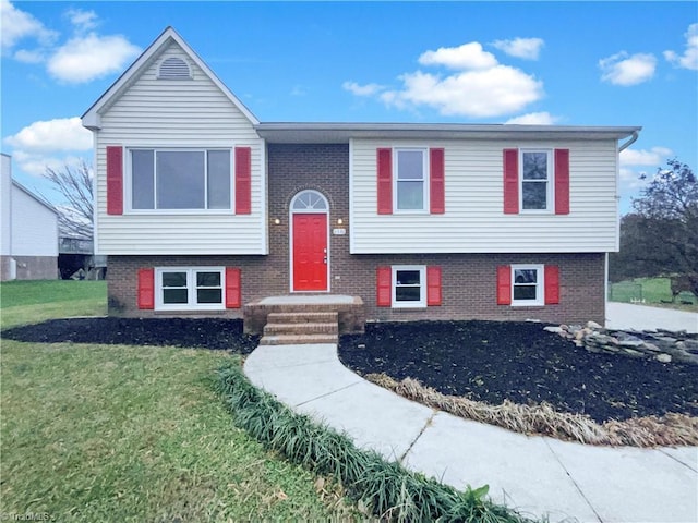 raised ranch featuring brick siding and a front lawn