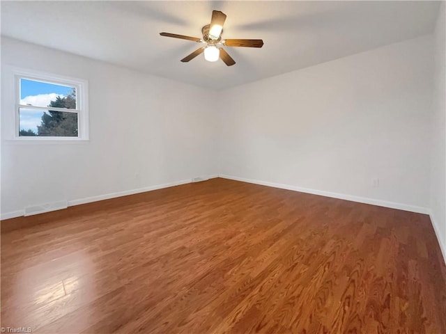 spare room with ceiling fan, baseboards, and dark wood-style flooring