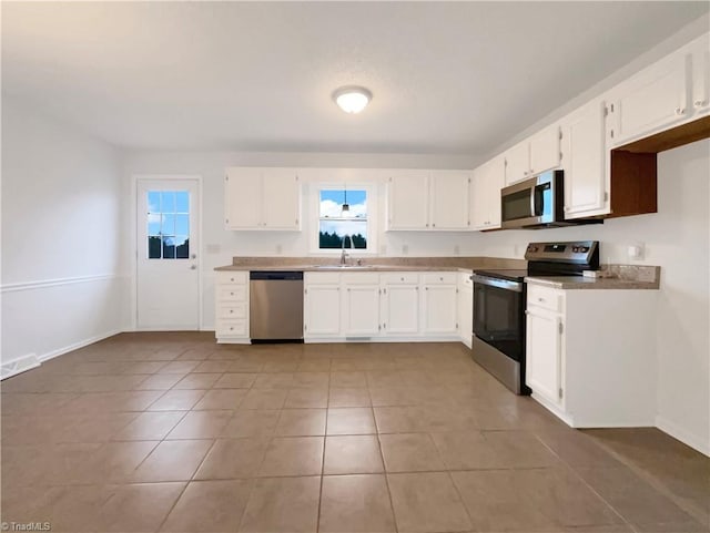 kitchen with stainless steel appliances, light countertops, white cabinets, and baseboards