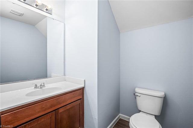 bathroom featuring vanity, visible vents, baseboards, lofted ceiling, and toilet