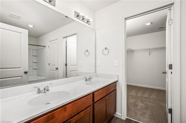 full bathroom with double vanity, baseboards, and a sink