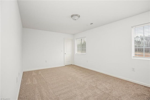 unfurnished room featuring baseboards, plenty of natural light, and light colored carpet