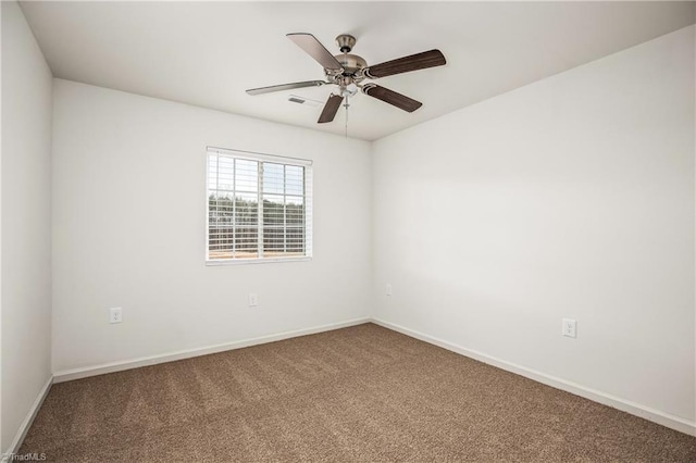 carpeted spare room with a ceiling fan and baseboards