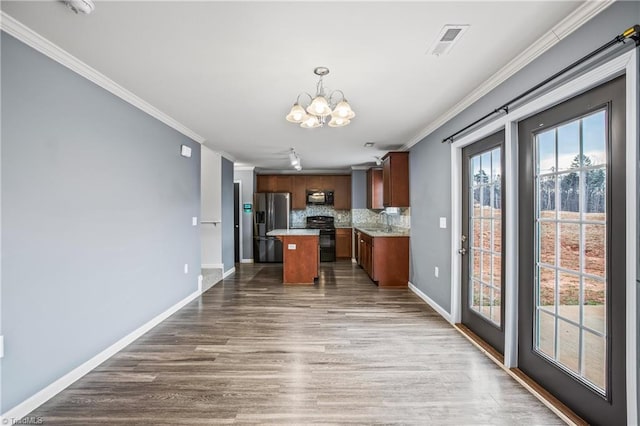 kitchen featuring a notable chandelier, black appliances, a sink, crown molding, and decorative backsplash