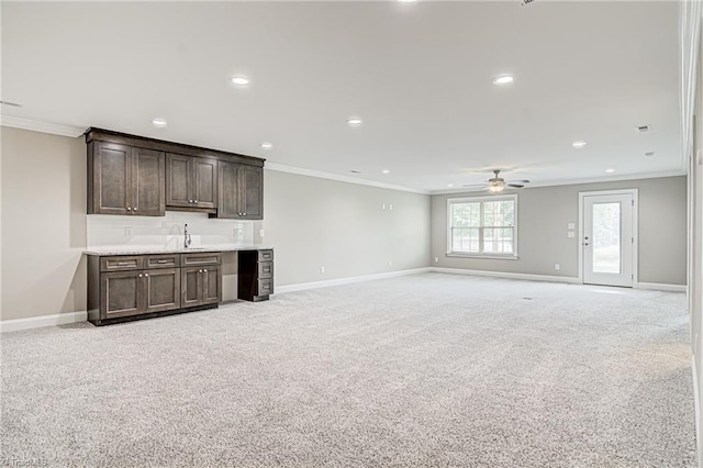 unfurnished living room featuring ceiling fan, light colored carpet, sink, and ornamental molding