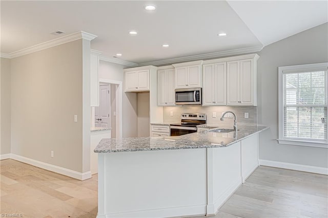 kitchen with appliances with stainless steel finishes, kitchen peninsula, white cabinetry, and light stone counters