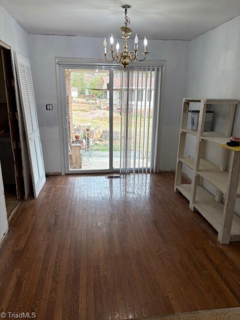 unfurnished dining area featuring dark hardwood / wood-style floors and a chandelier