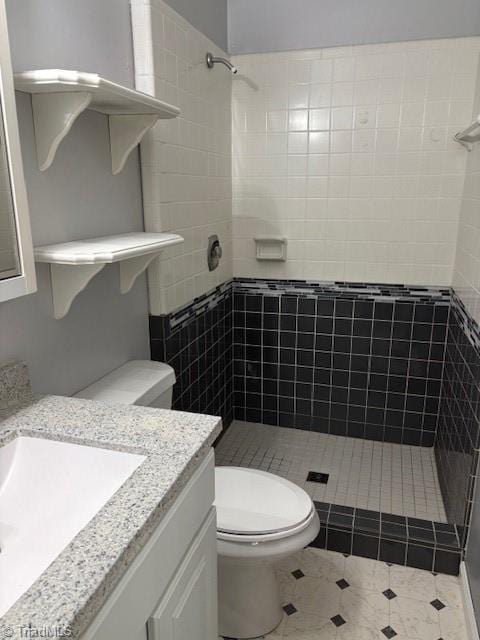 bathroom featuring vanity, tiled shower, and toilet