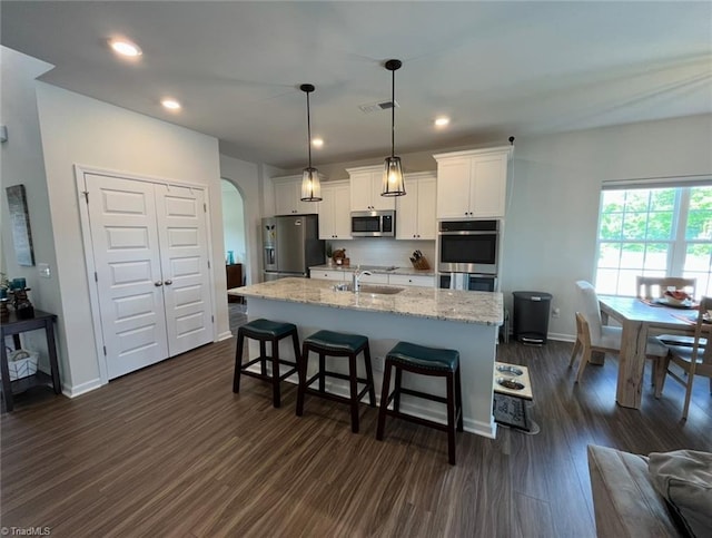 kitchen with visible vents, arched walkways, a sink, a breakfast bar, and stainless steel appliances