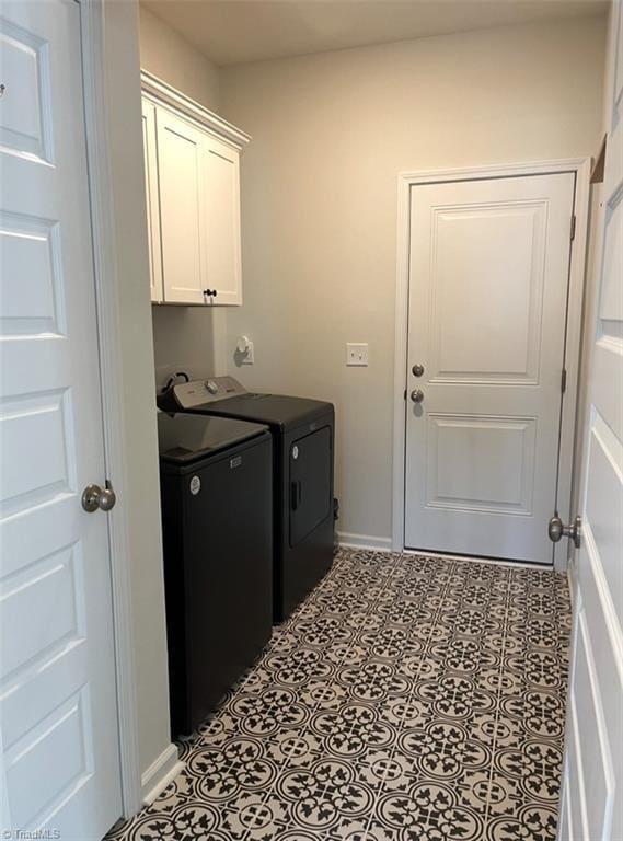 clothes washing area featuring baseboards, cabinet space, and washing machine and dryer
