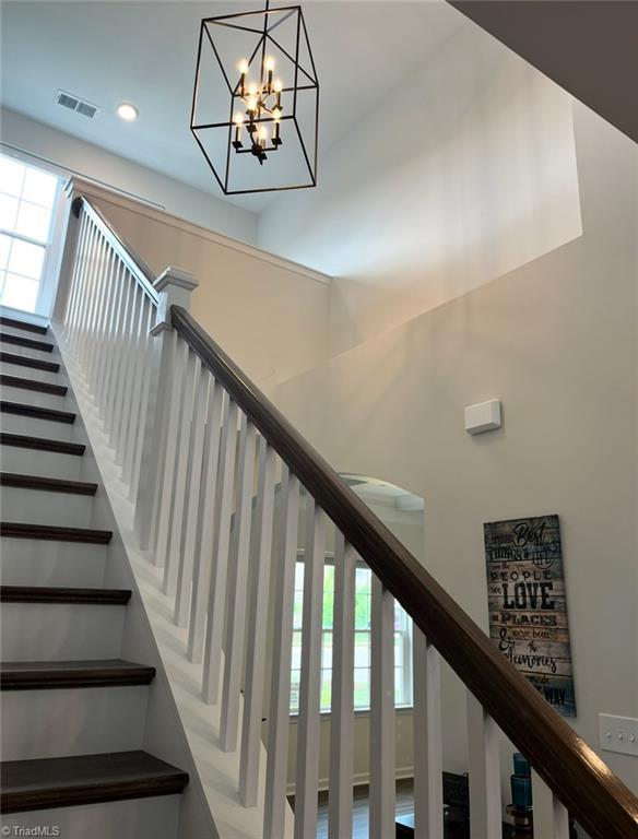 staircase with visible vents, recessed lighting, and a notable chandelier
