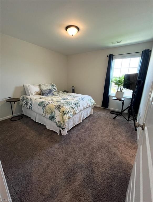 bedroom featuring dark colored carpet and baseboards