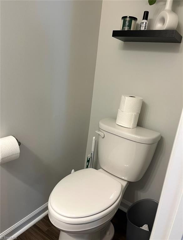 bathroom with toilet, baseboards, and wood finished floors