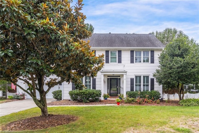 colonial house featuring driveway, a garage, fence, and a front yard