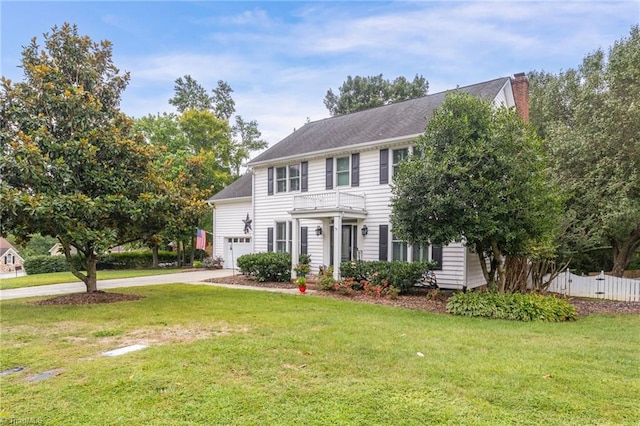 colonial-style house featuring a garage, a chimney, a front yard, and fence