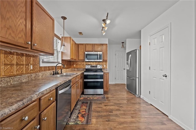 1310 Silver Dr, Mebane, NC 27302 - kitchen with appliances with stainless steel finishes, a sink, brown cabinets, backsplash, and dark wood-type flooring