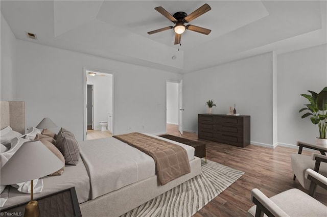 1310 Silver Dr, Mebane, NC 27302 - bedroom featuring a raised ceiling, wood finished floors, baseboards, connected bathroom, and ceiling fan