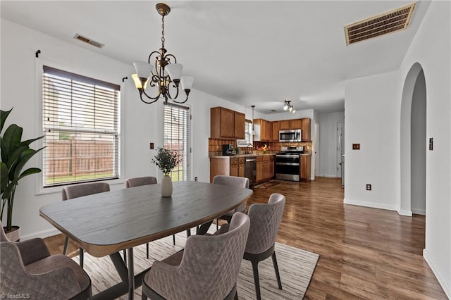 1310 Silver Dr, Mebane, NC 27302 - dining room with baseboards, arched walkways, dark wood-style flooring, and a chandelier