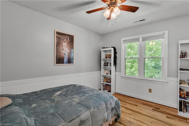 408 Camelot Dr, Salisbury, NC 28144 - bedroom featuring wainscoting, a textured ceiling, wood finished floors, and ceiling fan
