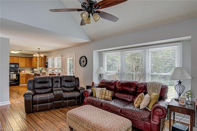 living room with light hardwood / wood-style flooring, ceiling fan with notable chandelier, plenty of natural light, and lofted ceiling