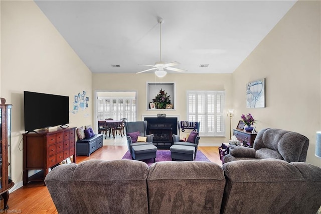 living area featuring visible vents, light wood-style floors, a fireplace, and a ceiling fan