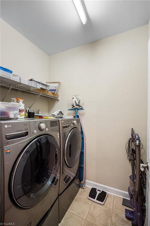 washroom with baseboards, independent washer and dryer, light tile patterned flooring, and laundry area