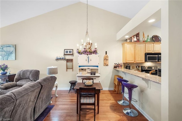 dining space featuring wood finished floors, baseboards, lofted ceiling, recessed lighting, and a chandelier