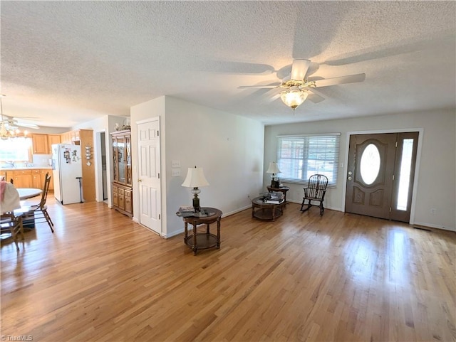 foyer entrance featuring ceiling fan, light hardwood / wood-style flooring, and a textured ceiling