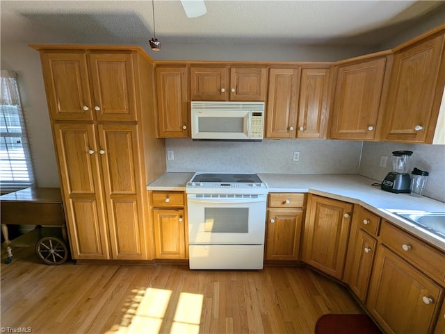 kitchen with a textured ceiling, decorative backsplash, light hardwood / wood-style flooring, and white appliances