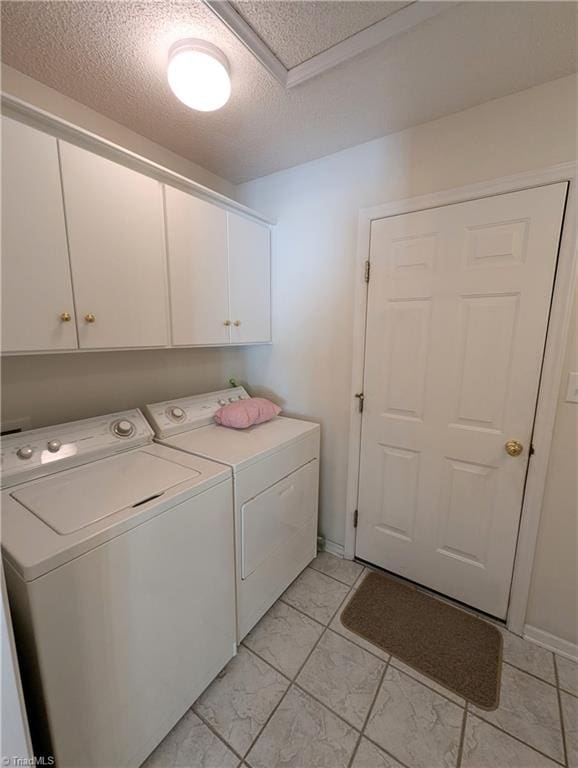 laundry room with cabinets, a textured ceiling, and washing machine and dryer