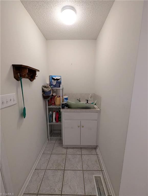 laundry area featuring sink and a textured ceiling