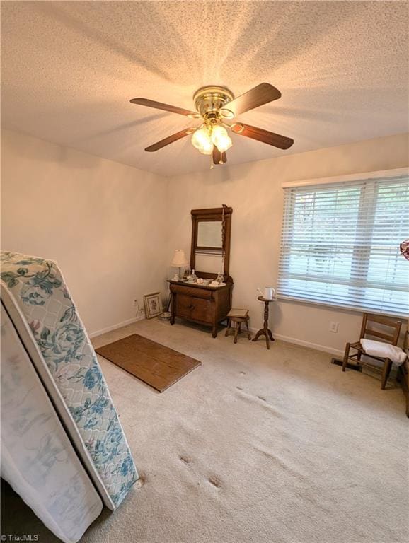 living area with carpet, a textured ceiling, and ceiling fan