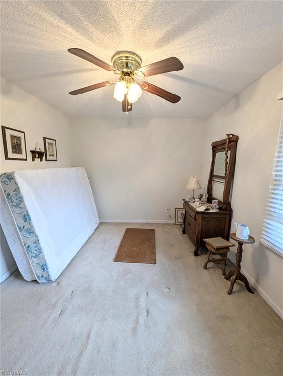 carpeted bedroom with ceiling fan and a textured ceiling