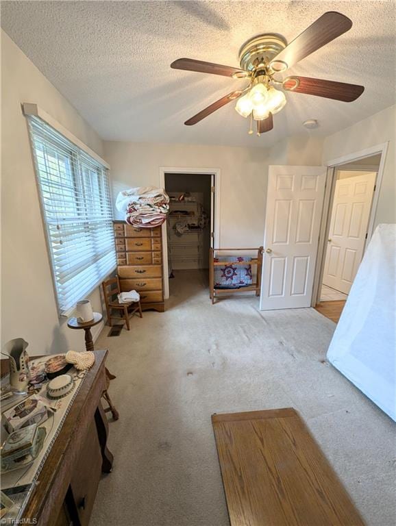 miscellaneous room with ceiling fan, light colored carpet, and a textured ceiling