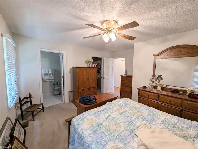 bedroom featuring ensuite bathroom, ceiling fan, a textured ceiling, multiple windows, and light colored carpet