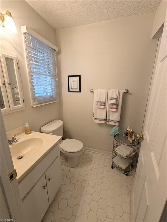 bathroom featuring tile patterned flooring, a textured ceiling, vanity, and toilet