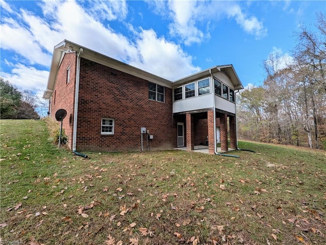 back of house with a lawn, a sunroom, and a patio area