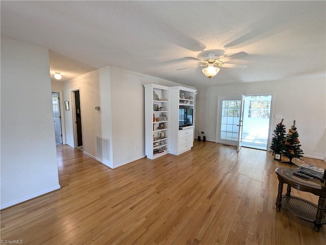 interior space with ceiling fan, a textured ceiling, and light wood-type flooring