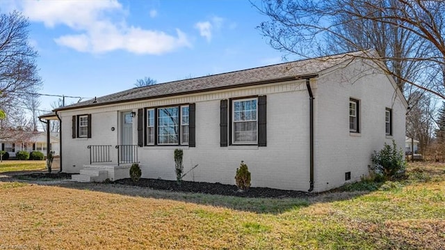 view of front of property with brick siding, crawl space, and a front yard