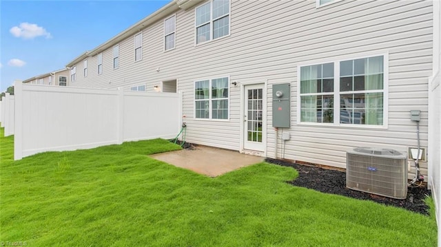 rear view of property featuring a lawn and central AC unit