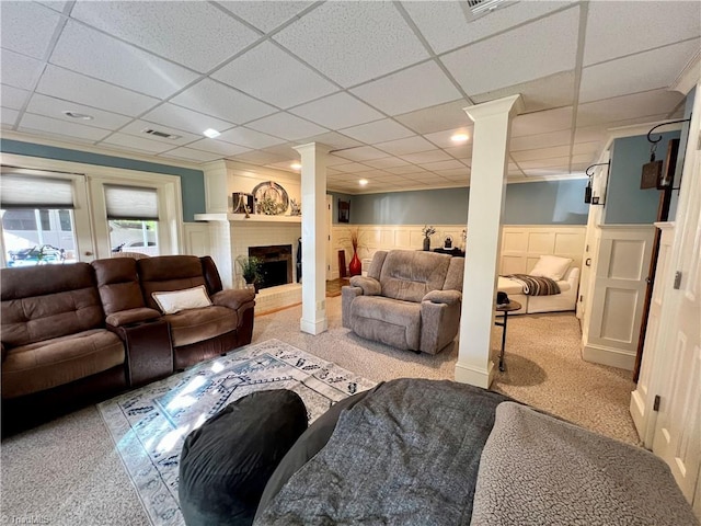 carpeted living room with decorative columns and a drop ceiling