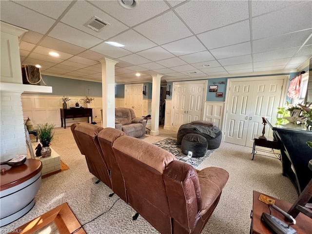 living room featuring carpet flooring, ornate columns, and a paneled ceiling