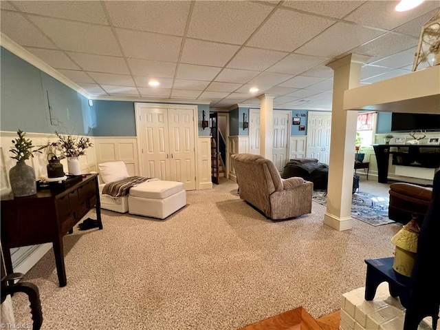 living room featuring carpet floors, ornate columns, and a drop ceiling