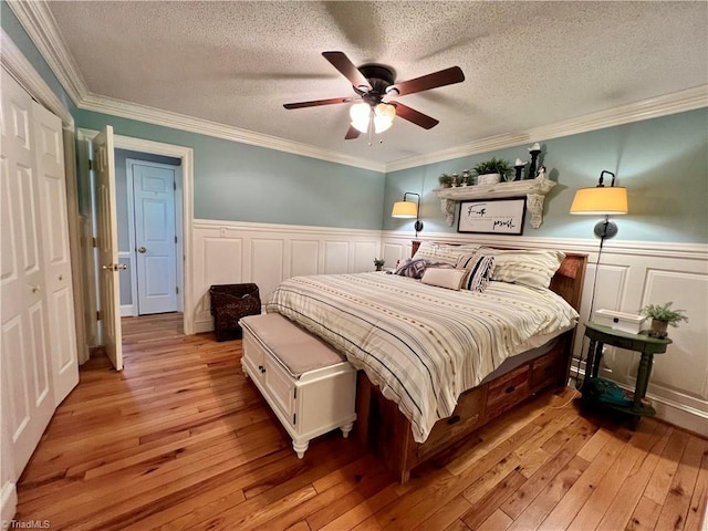 bedroom featuring ceiling fan, a closet, crown molding, light hardwood / wood-style flooring, and a textured ceiling