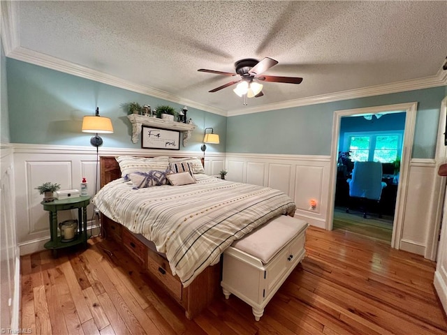 bedroom featuring light hardwood / wood-style floors, a textured ceiling, ornamental molding, and ceiling fan